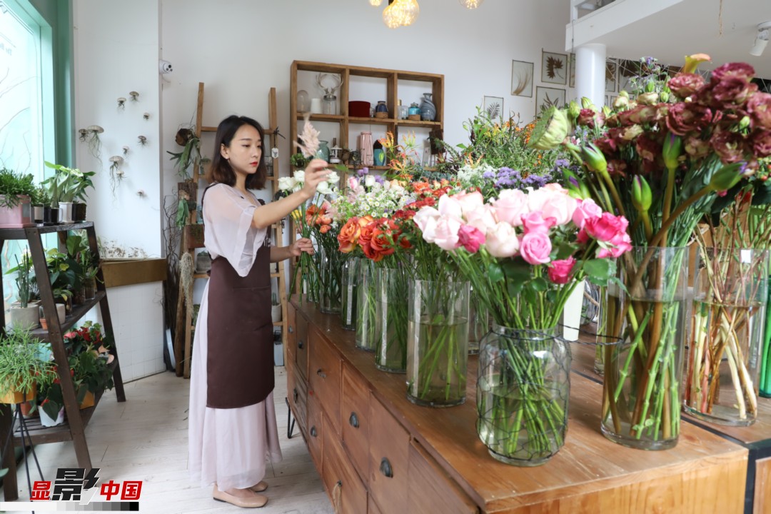 王黎媛是一名河南姑娘，在昆明念完大學(xué)后，就再也舍不下春城的藍(lán)天陽(yáng)光、青山碧水，更舍不下這里的四時(shí)繁花，于是就干脆留了下來(lái)，成了一名媒體人。2017年的時(shí)候又毅然辭去工作，創(chuàng)業(yè)開(kāi)起了花店，成了都市里的一名“花房姑娘”。圖為王黎媛在自己的花店中整理鮮花。新華網(wǎng) 周亞平/攝 念新洪/文